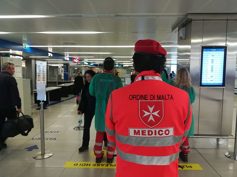 Civil protection volunteers engaged in health checks at Milan Malpensa airport.