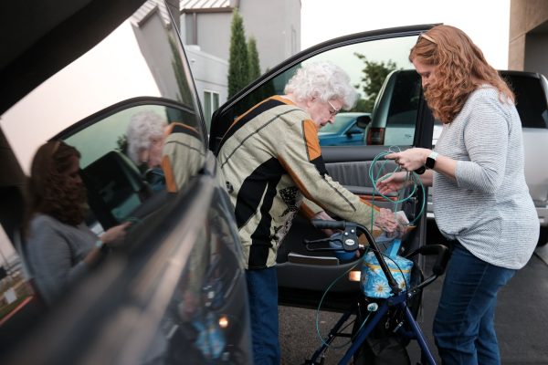 Tiffany Jones, right, helps Shirley Porch with her oxygen mask tubing as she arrives at a hotel in Wichita, Kan.