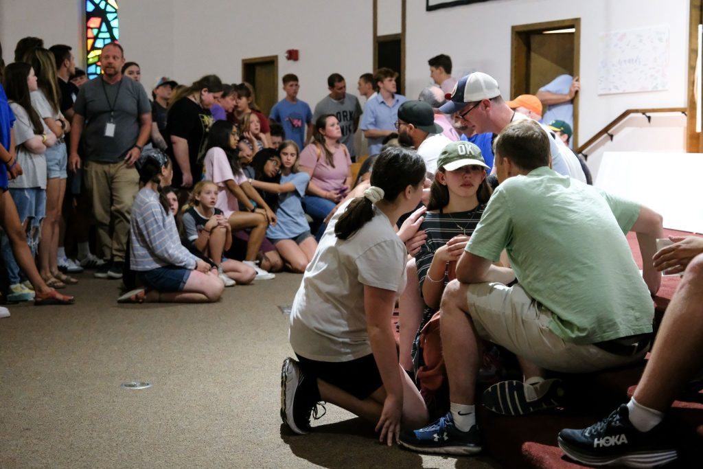 Students kneel at the front of the East Hill Church of Christ auditorium during the invitation after evening worship.