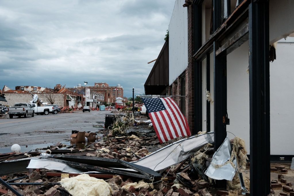 An American flag flaps in the wind, surrounded by rubble in downtown Sulphur, Okla.