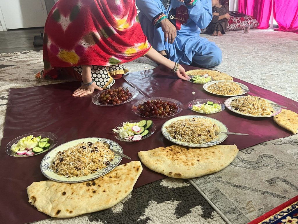 An Afghan refugee woman feeds Dan and Mary Huber at her San Antonio apartment.