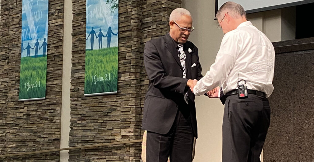 Ministers Tim Luster, left, and Tim Pyles pray at a joint assembly of their Tulsa-area congregations.