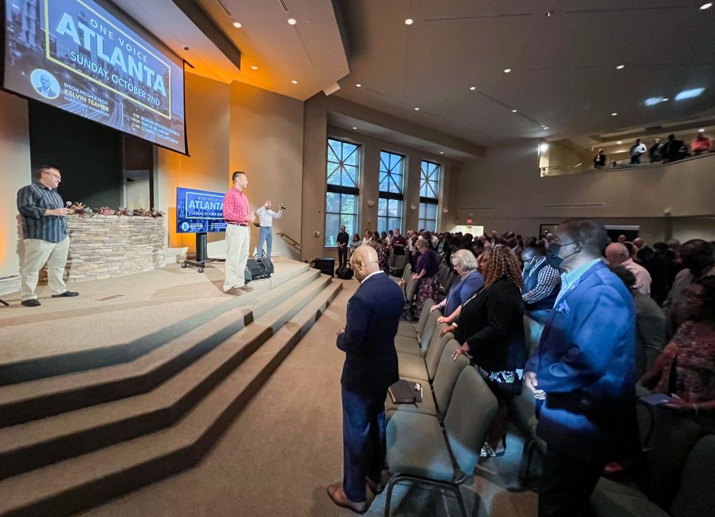 Paul Huyghebaert, on stage, welcomes attendees to the "One Voice Atlanta" joint assembly.