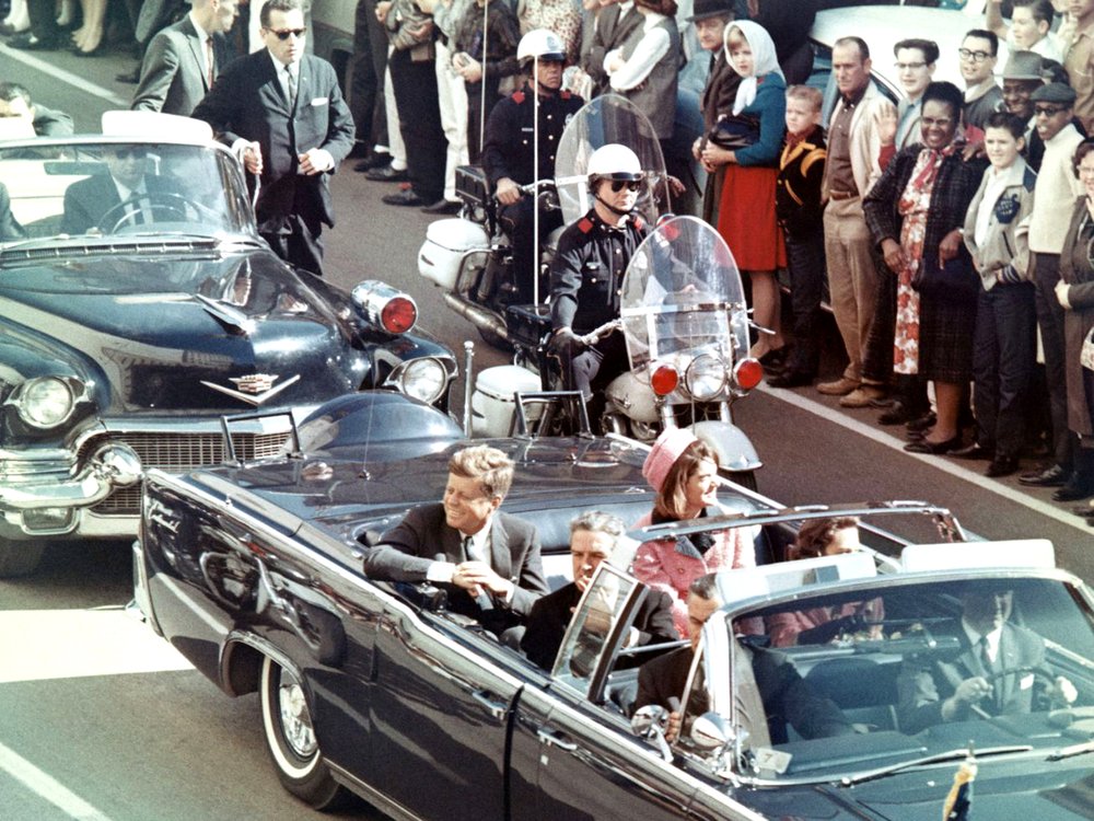 President John F. Kennedy rides in the limousine in Dallas minutes before the 1963 assassination.