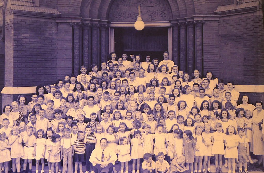 Students and teachers at a mid-1940s Lindsley Avenue Vacation Bible School crowd the church building entrance. Seated in the bottom row, a smiling Ira North reflects the day’s excitement.