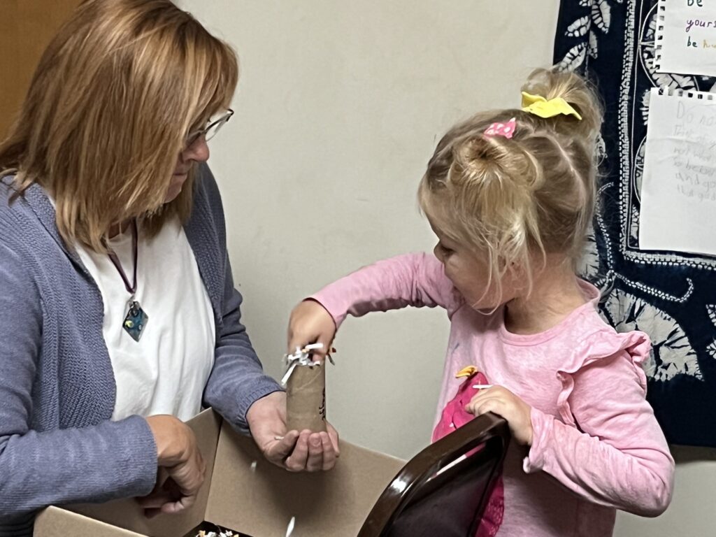 Karen Swan, director of Redwood Montessori School in Lebanon, Ind., helps a student prepare a “fire stick” for Malawi.