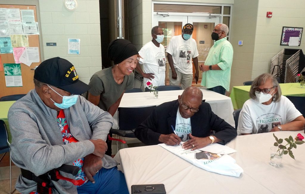 Fred Gray, who received the Presidential Medal of Freedom, signs a T-shirt picturing him with President Joe Biden.