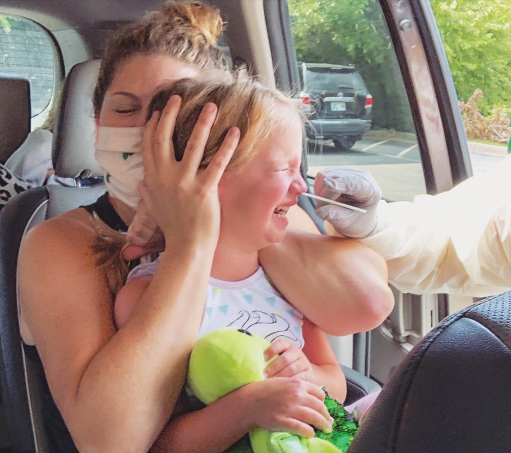 Laura Akins holds her 5-year-old daughter, Scout, during a nasal swab test for COVID-19. Akins, reviews editor for The Christian Chronicle, survived the coronavirus along with her husband and four children.