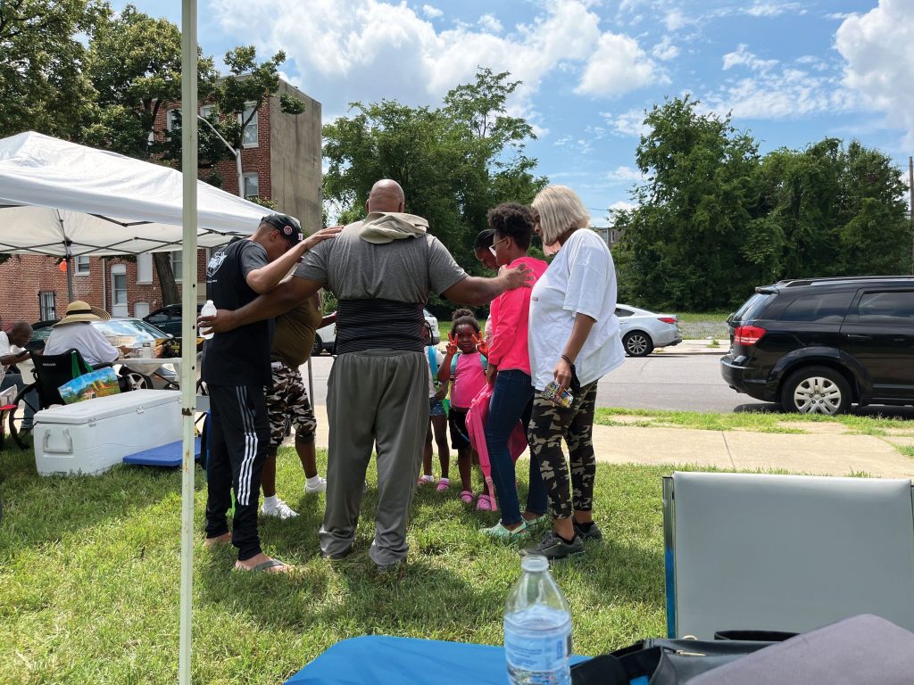 Davis Worley, minister for the Sandtown Church of Christ, prays over a family during the church’s back to school campaign.