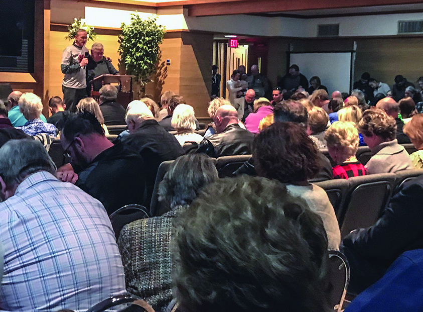 Elder Mike Tinius, left, wraps an arm around minister Britt Farmer as he leads the West Freeway church in prayer Monday night.