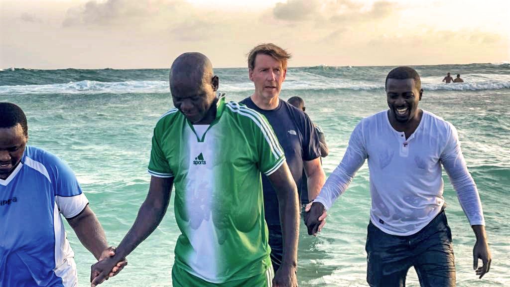 John Bosco (in green) emerges from the Indian Ocean after his baptism.