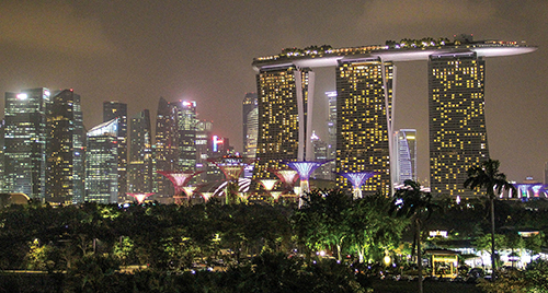 The luxurious Marina Bay Sands Hotel towers over a grove of “supertrees” — solar-powered