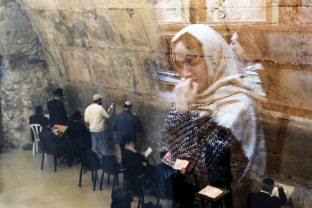 A praying woman is reflected by the one-way glass that separates the sections for men and women at the Western Wall in the Old Town of Jerusalem.