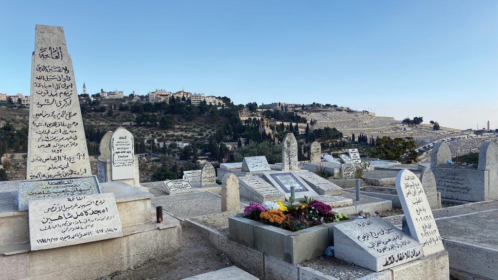 Gravestones in Arabic stand in the Islamic Bab al-Rahma Cemetery along the eastern wall of the Temple Mount in Jerusalem. Behind them in the distance is Mount of Olives Jewish Cemetery, the oldest Jewish cemetery in Jerusalem.