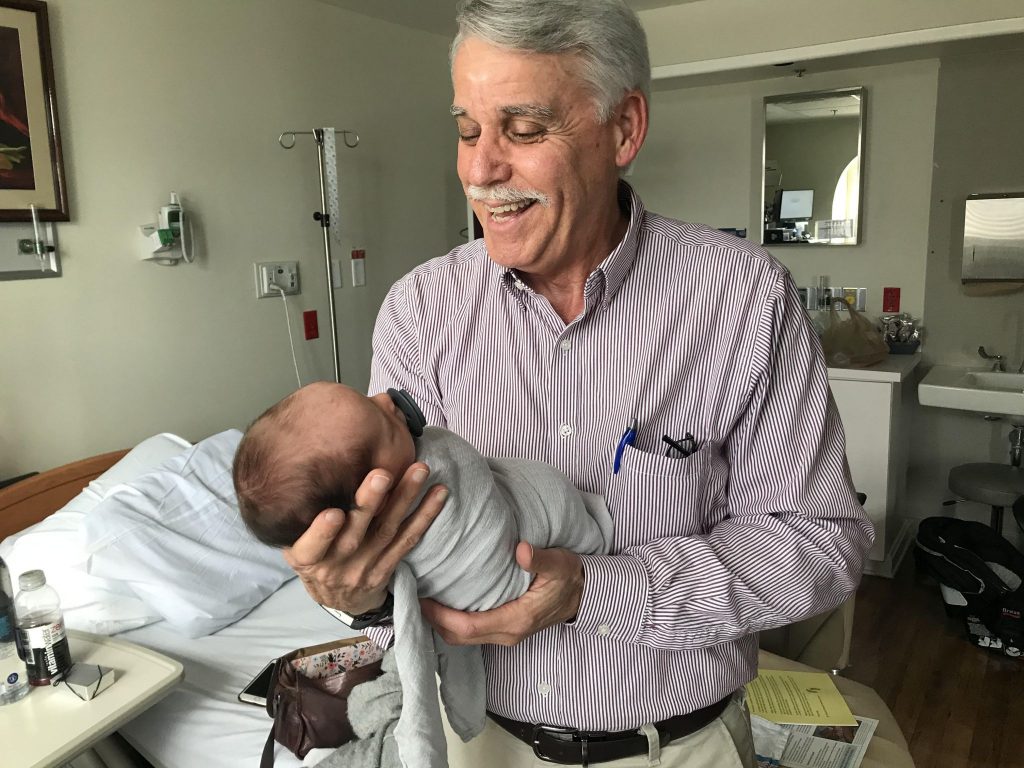 Jerry Callens holds a newborn baby in a hospital.